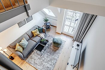 The photo shows a living room with a couch, carpet and TV photographed from a high angle