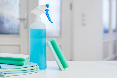 The photo shows a spray bottle, sponges and rags for cleaning