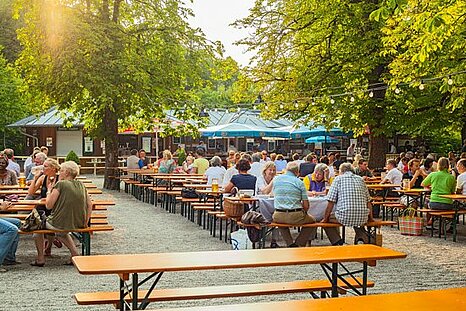The photo shows a lively beergarden with benches and tables