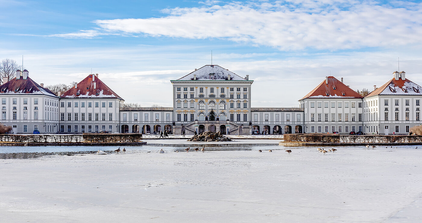 Zu sehen ist das Nymphenburger Schloss im Winter, im Vordergrund ist Schnee