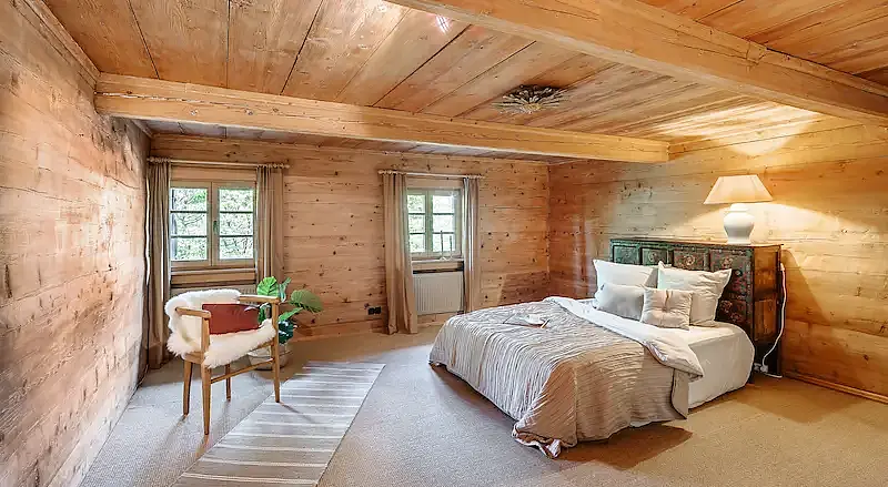 Schlafzimmer in einem alpenländischen Landhaus am Tegernsee mit Holzvertäfelung