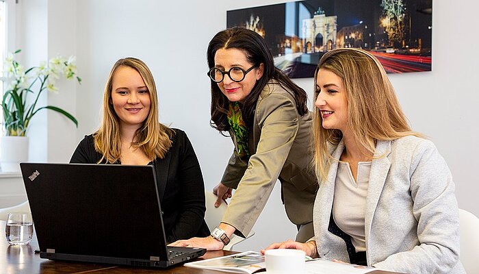 Mitarbeiterinnnen von Mr. Lodge sehen sich gemeinsam etwas auf einem Laptop an.