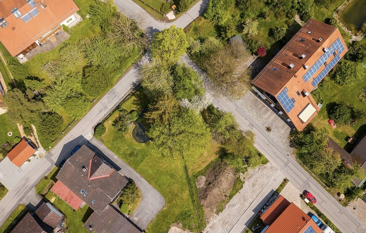 Luftaufnahme eines grünen Baugrundstücks zwischen Wohnhäusern in einer ländlichen Gegend